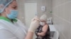 A nurse at Russia's Kemerovo Clinical Diagnostic Center prepares to vaccinate fellow nurse Olga Skripachenko with the Sputnik-V vaccine on December 9, 2020.